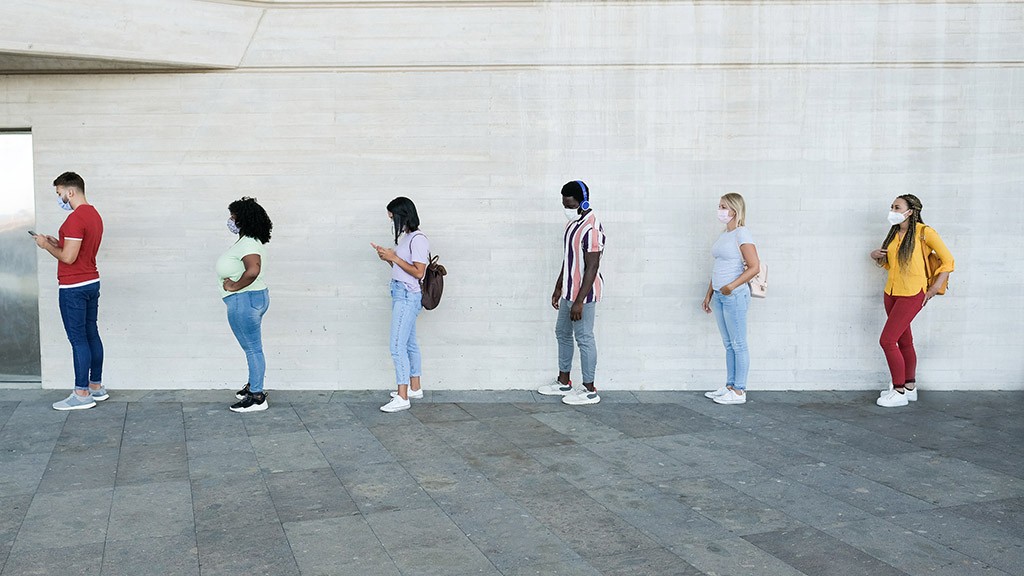 Multiracial people standing in a queue and waiting – Young people with social distancing and wearing protective face masks – Concept of the new normality and social distancing